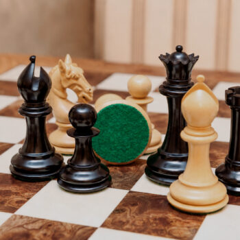 Close-up of Chevalier ebony and boxwood chess pieces with a green felt base