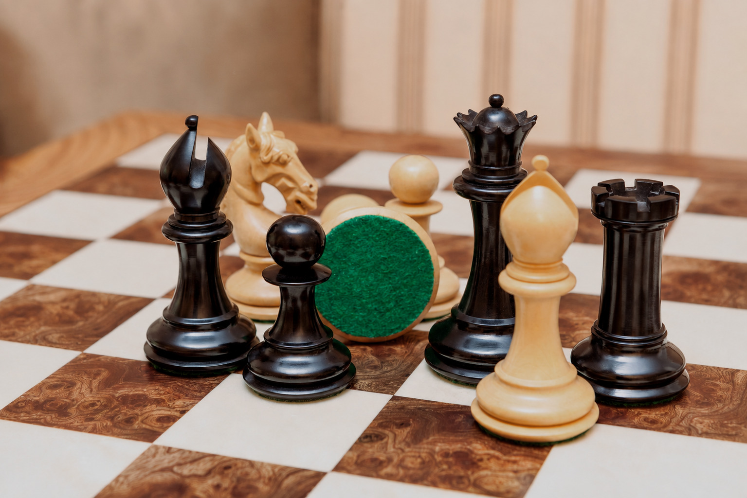 Close-up of Chevalier ebony and boxwood chess pieces with a green felt base