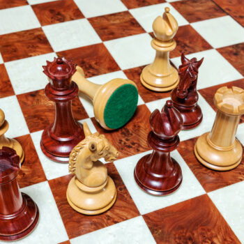 Overhead view of Chevalier padauk and boxwood chess pieces with a green felt base on the 60 cm Toscana chess board