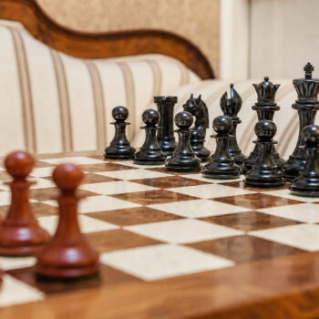 Chevalier ebony and padauk chess pieces set up for play on a wooden chess board