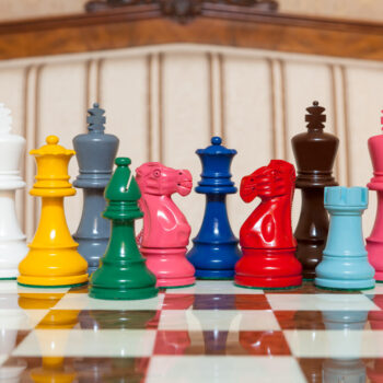 Earl lacquered boxwood chess pieces in assorted colours on a red-and-white chess board