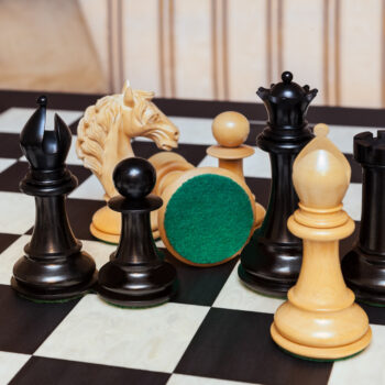Shown with: 60 cm Asturias chess board Close-up of Florence ebony and boxwood chess pieces with a green felt base on the 60 cm Asturias chess board