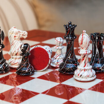 Shown with: 51 cm Bologna chess board Close-up of New York black-and-white splatter chess pieces with a red felt base on the 51 cm Bologna chess board