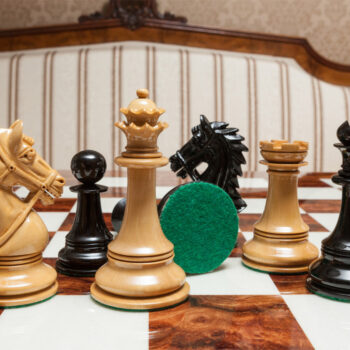 Close-up of Regal lacquered ebony and boxwood chess pieces with a green felt base on the 60 cm Da Vinci chess board