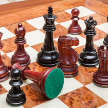 Shown with: 51 cm Venezia chess board Overhead close-up of Viking lacquered padauk and ebony chess pieces with a fallen pawn on the 51 cm Venezia chess board